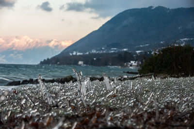 Scenic view of sea by mountains against sky during sunset