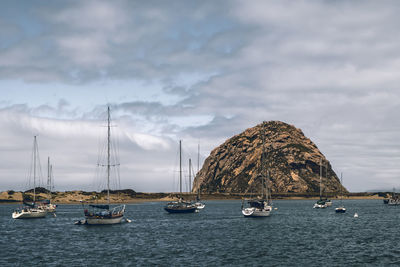 Sailboats moored in sea against sky