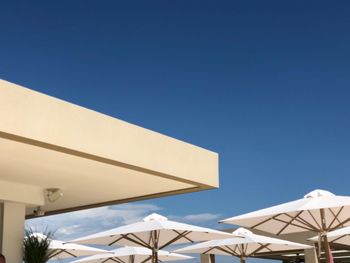 Low angle view of parasol against clear blue sky