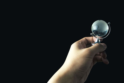 Midsection of person holding glass against black background