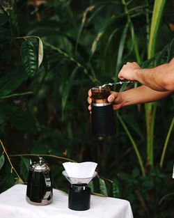 Midsection of person preparing coffee on table