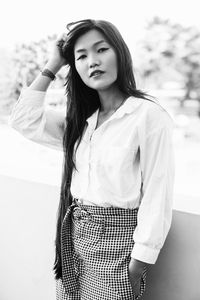 Portrait of young woman standing against wall