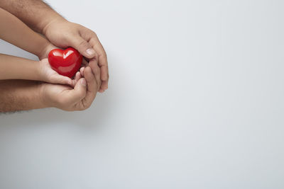 Close-up of hand holding red over white background
