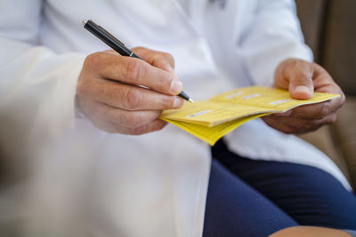 Close-up of doctor writing in vaccination pass