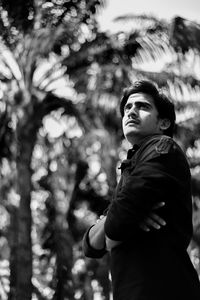 Low angle view of young man standing against tree