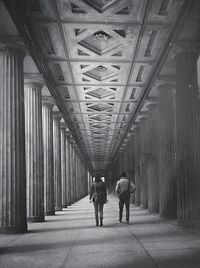 Black and white image of people walking through a gallery