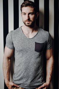 Portrait of young man standing against wall