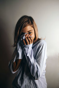 Portrait of girl covering face against gray background