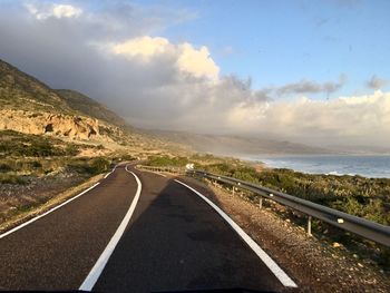 Road leading towards mountains against sky