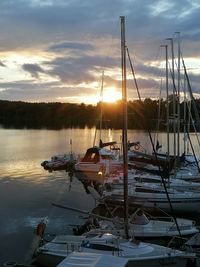 Sailboats moored in sea at sunset