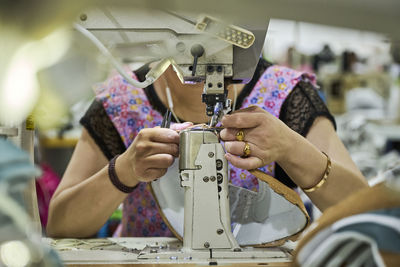 Detail of worker's hands doing sewing in the leather of the shoes at chinese shoes factory