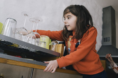 Curious girl searching on shelf in kitchen at home