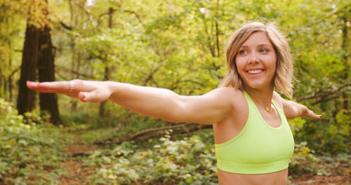 Smiling young woman exercising in forest