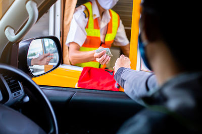 Cropped image of man paying at tollbooth from car