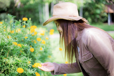 Side view of woman wearing hat standing by plants