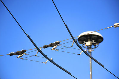 Low angle view of power lines against clear blue sky