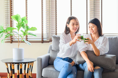 Portrait of smiling young woman sitting on sofa at home