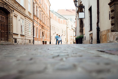 Rear view of woman walking on street amidst buildings in city