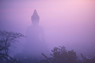 Silhouette of statue against sky during foggy weather