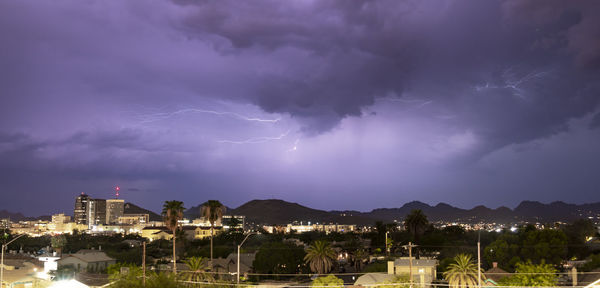 Lightning over illuminated buildings in city at night