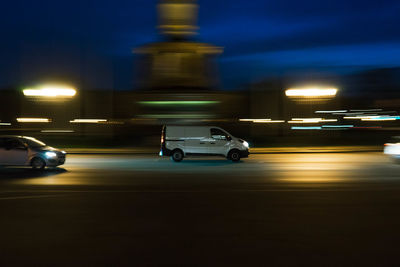 Cars on illuminated city street at night