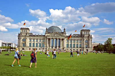 People at reichstag building against sky