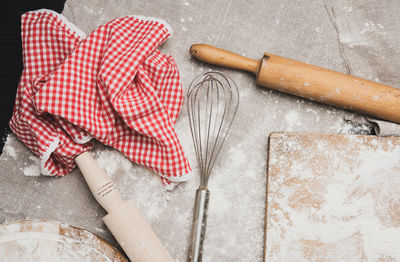 Metal hand mixer, wooden rolling pins and sprinkled flour on a wooden board, top view