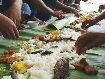 Cropped image of people eating food on banana leaves