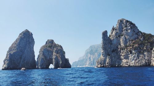 Panoramic view of sea and rocks against clear blue sky