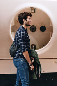 Portrait of young man standing against wall