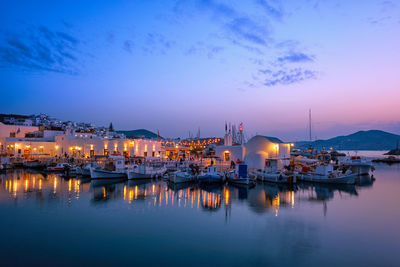 Sailboats moored in harbor at dusk