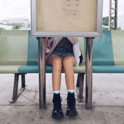 Low section of woman sitting at bus stop