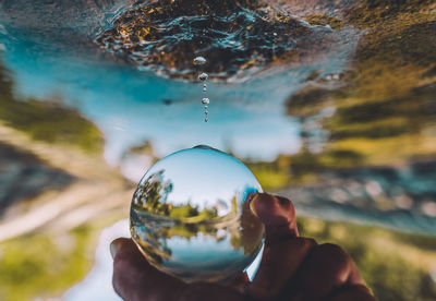 Close-up of hand holding crystal ball against blurred background