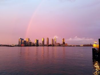 East river by cityscape against cloudy sky at dusk