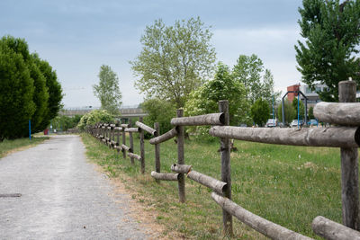 Footpath by fence against sky