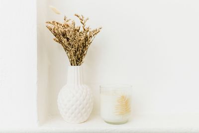Close-up of white jar on table against wall