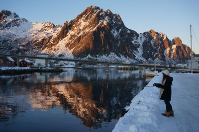 Frozen lake by snowcapped mountain against sky