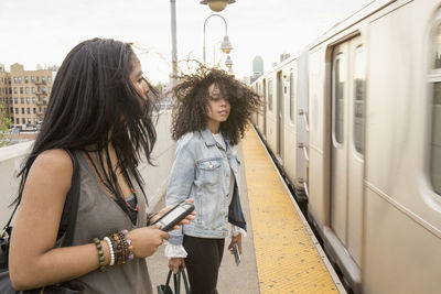 Woman standing by train in city