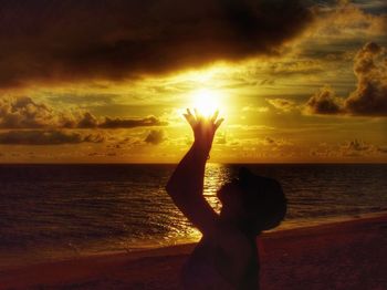 Woman standing at beach against sky during sunset