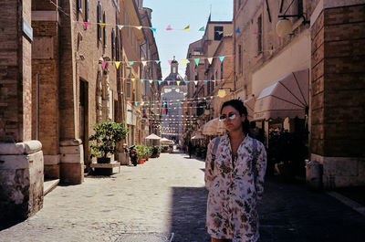 Woman standing amidst buildings in city