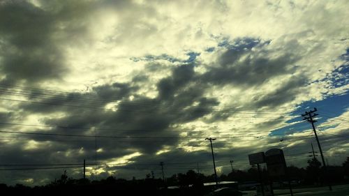 Low angle view of electricity pylon against cloudy sky