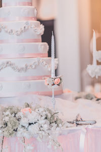 Close-up of candle and wedding cake on table