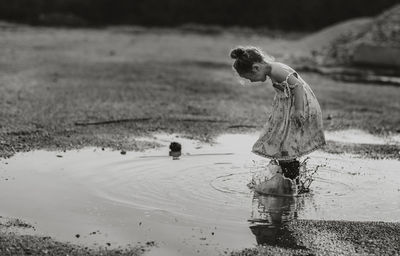 Full length of girl splashing water from puddle at beach