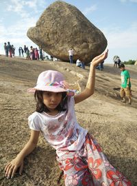 Optical illusion of girl holding boulder 