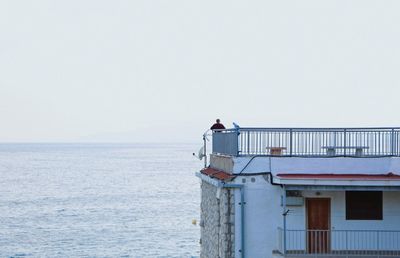 Bird perching on sea against clear sky