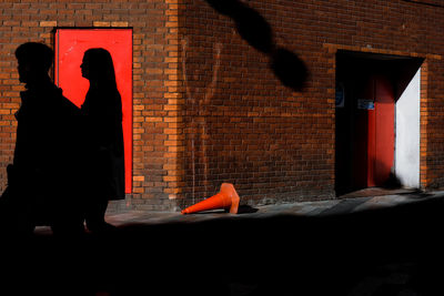 Shadows of two people against brick wall