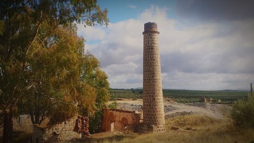 Old tower on field against sky