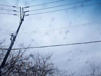 Low angle view of birds perching on cable against sky