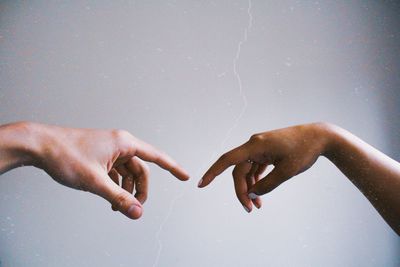 Cropped hands of women reaching against sky
