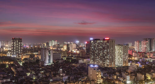 Illuminated buildings in city against sky at night